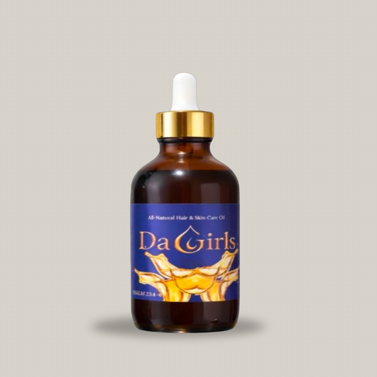 Bottle of Da Girls all-natural hair and skin care oil with a dropper on a gray background