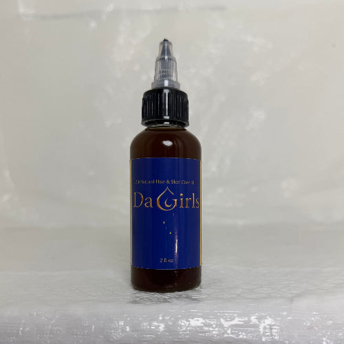 Bottle of Da Girl hair product on a textured white surface